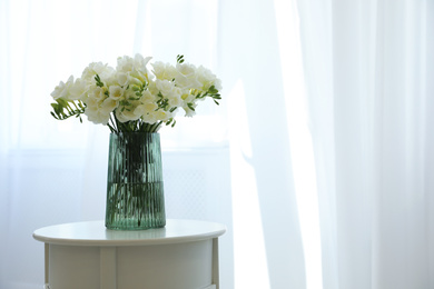 Photo of Beautiful bouquet with fresh freesia flowers on table indoors. Space for text