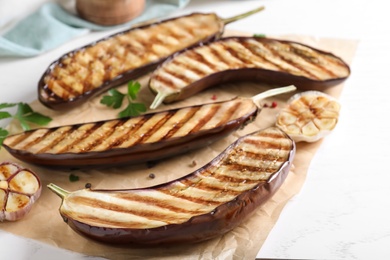Photo of Delicious grilled eggplant halves on white wooden table, closeup