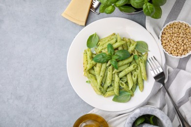Photo of Delicious pasta with pesto sauce and basil on light grey table, flat lay. Space for text