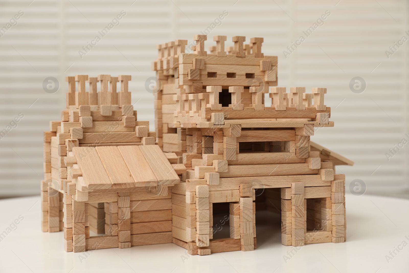 Photo of Wooden castle on white table indoors. Children's toy