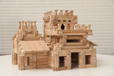 Photo of Wooden castle on white table indoors. Children's toy