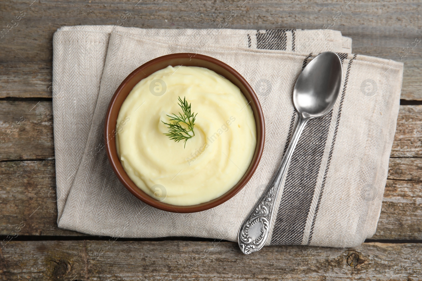 Photo of Freshly cooked homemade mashed potatoes with spoon and napkin on wooden table, top view