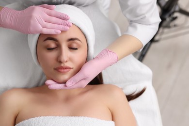 Cosmetologist making face massage to client in clinic, top view