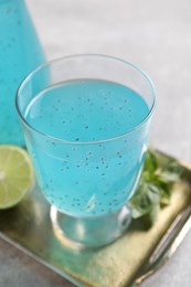 Tasty light blue drink with basil seeds on grey table