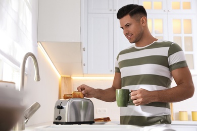 Photo of Man using modern toaster at kitchen counter