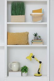 Photo of Shelves with lamp, books and different decor indoors. Interior design