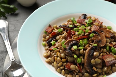 Delicious lentils with mushrooms, bacon and green onion on table, closeup