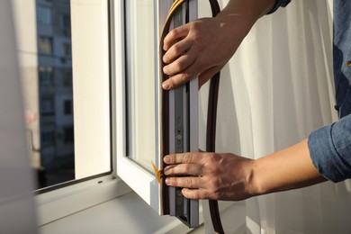 Construction worker putting sealing foam tape on window, closeup