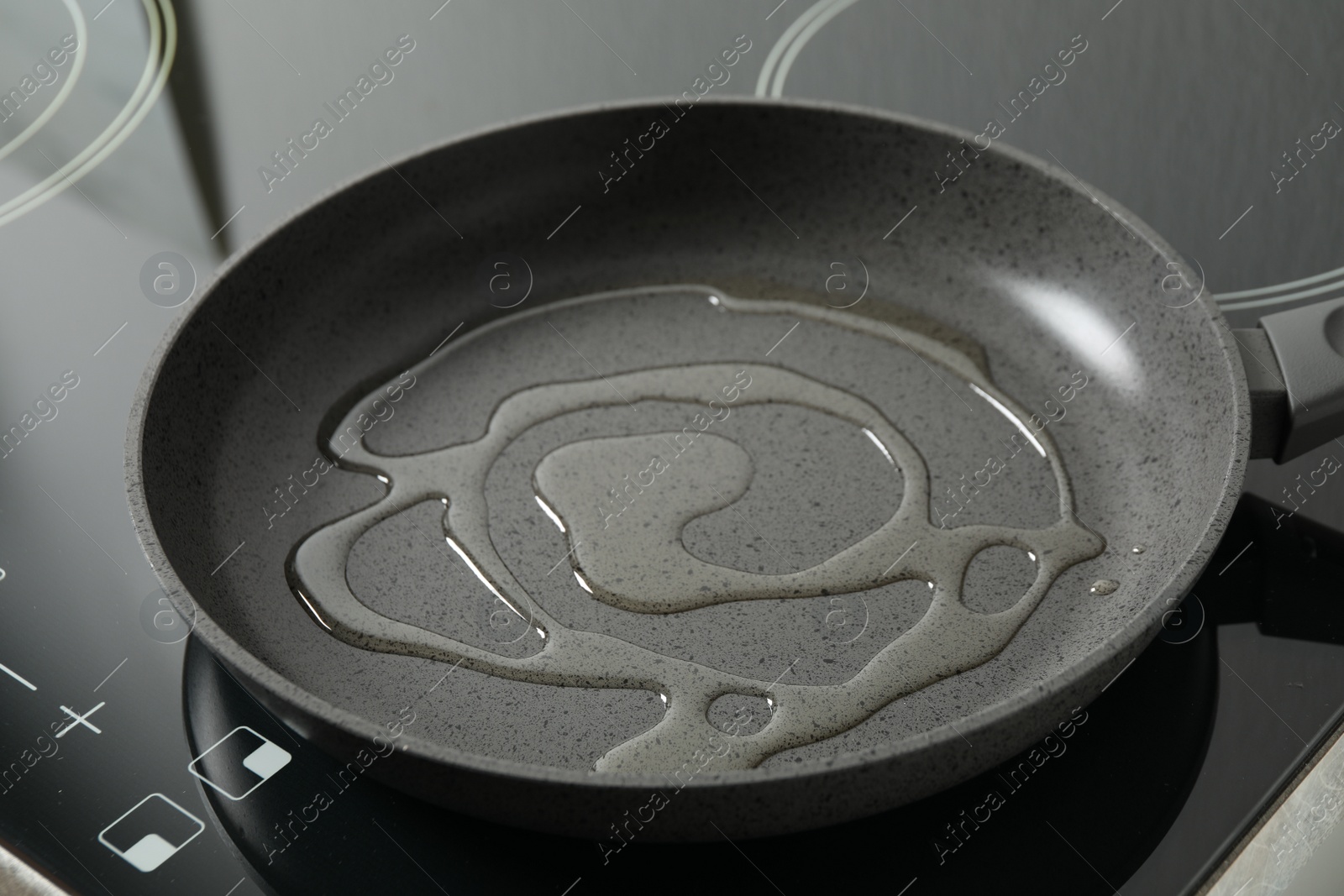 Photo of Frying pan with cooking oil on induction stove