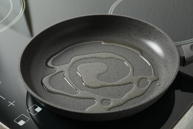 Photo of Frying pan with cooking oil on induction stove