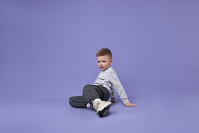 Photo of Happy little boy dancing on violet background