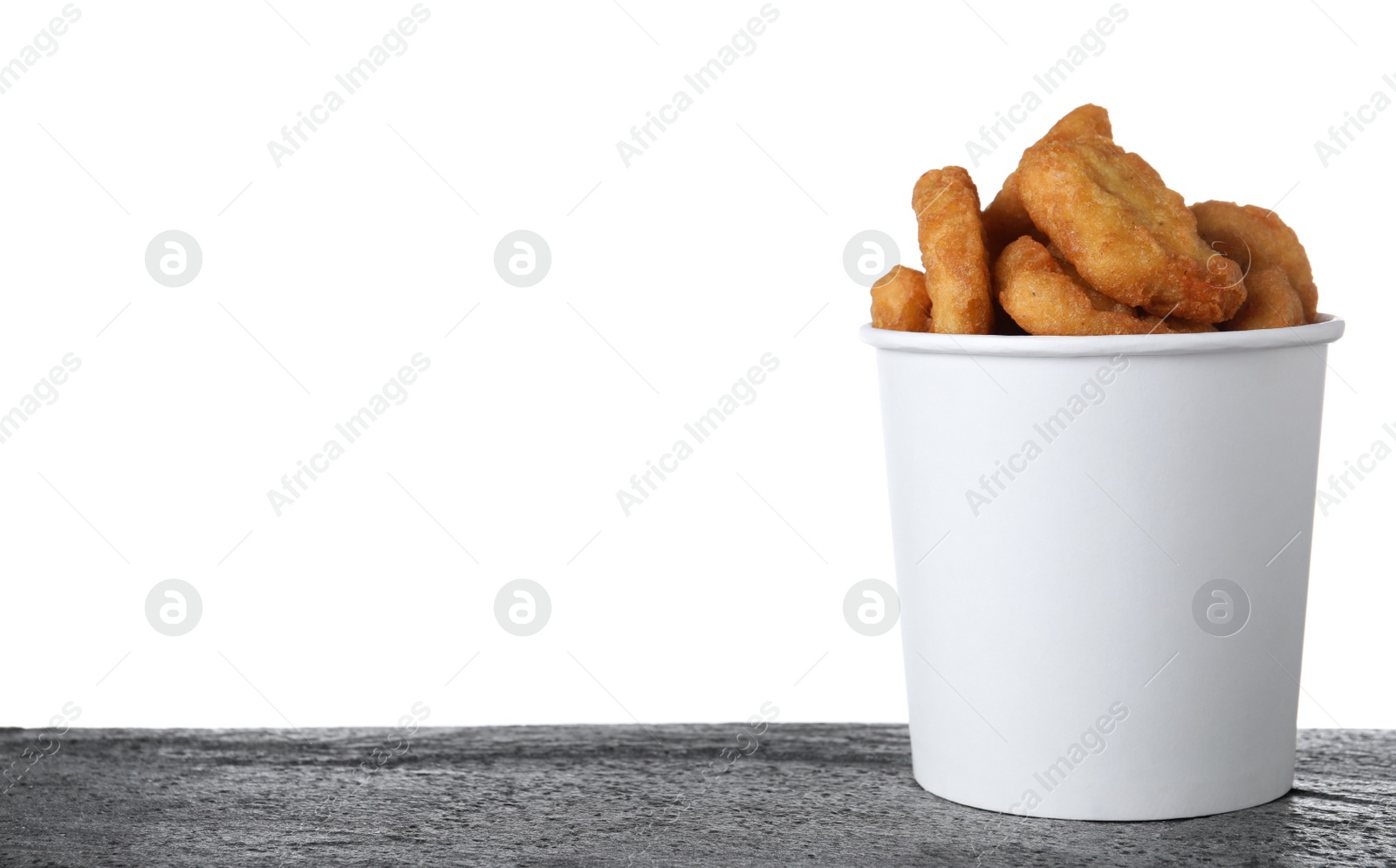 Photo of Bucket with tasty chicken nuggets on grey table against white background. Space for text