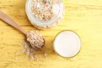 Glass with oat milk and flakes on wooden background