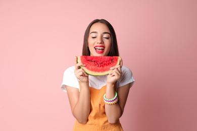 Beautiful young woman posing with watermelon on color background