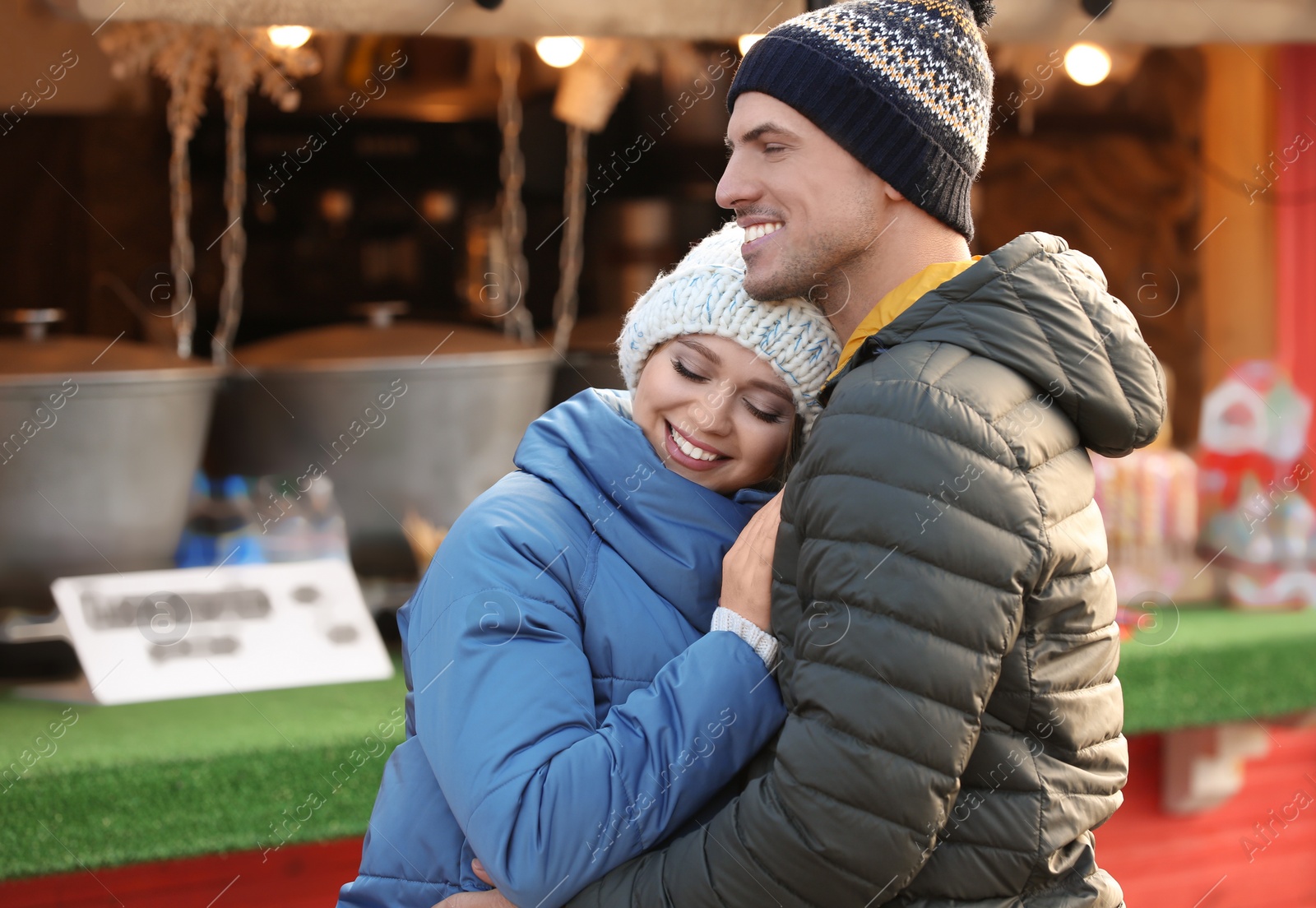 Photo of Happy couple in warm clothes at winter fair. Christmas season