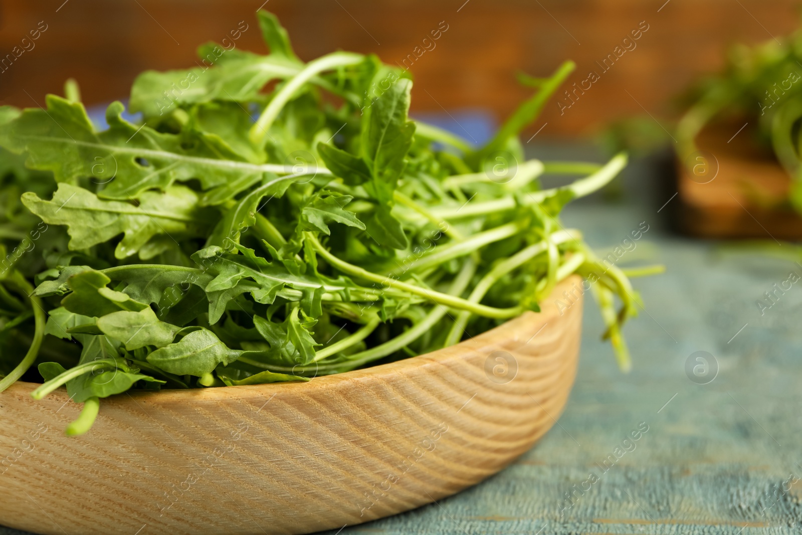 Photo of Fresh arugula on blue wooden table, closeup