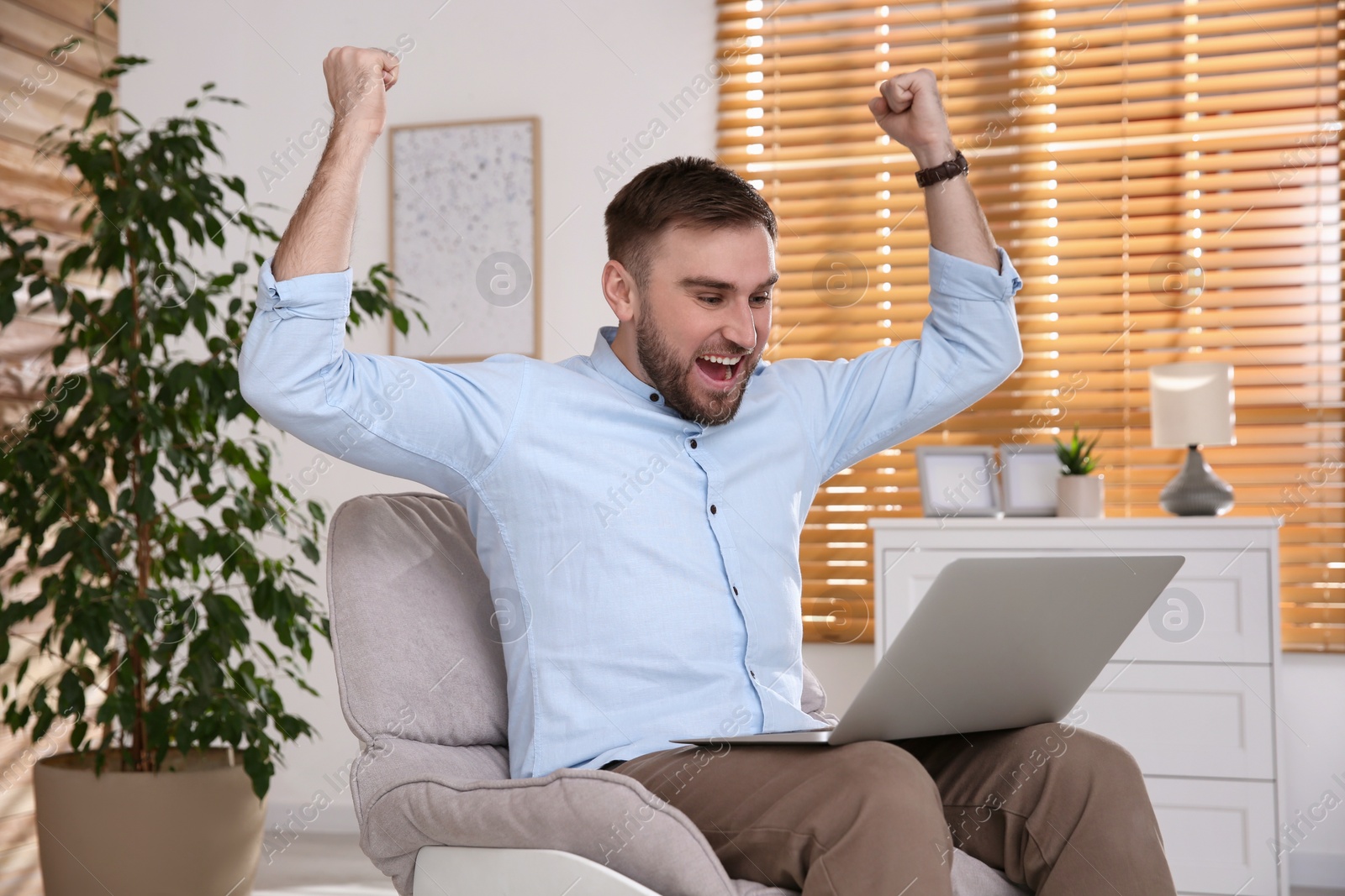 Photo of Emotional man participating in online auction using laptop at home