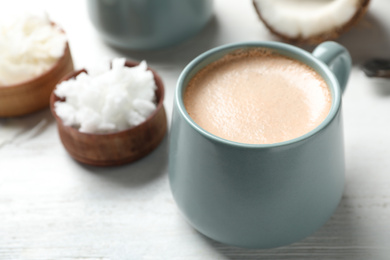 Photo of Delicious coffee with organic coconut oil on white wooden table