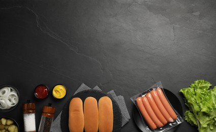 Different tasty ingredients for hot dog on dark table, flat lay. Space for text