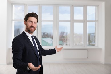 Photo of Happy real estate agent showing new apartment. Space for text