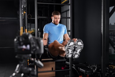 Man recording workout on camera at gym. Online fitness trainer