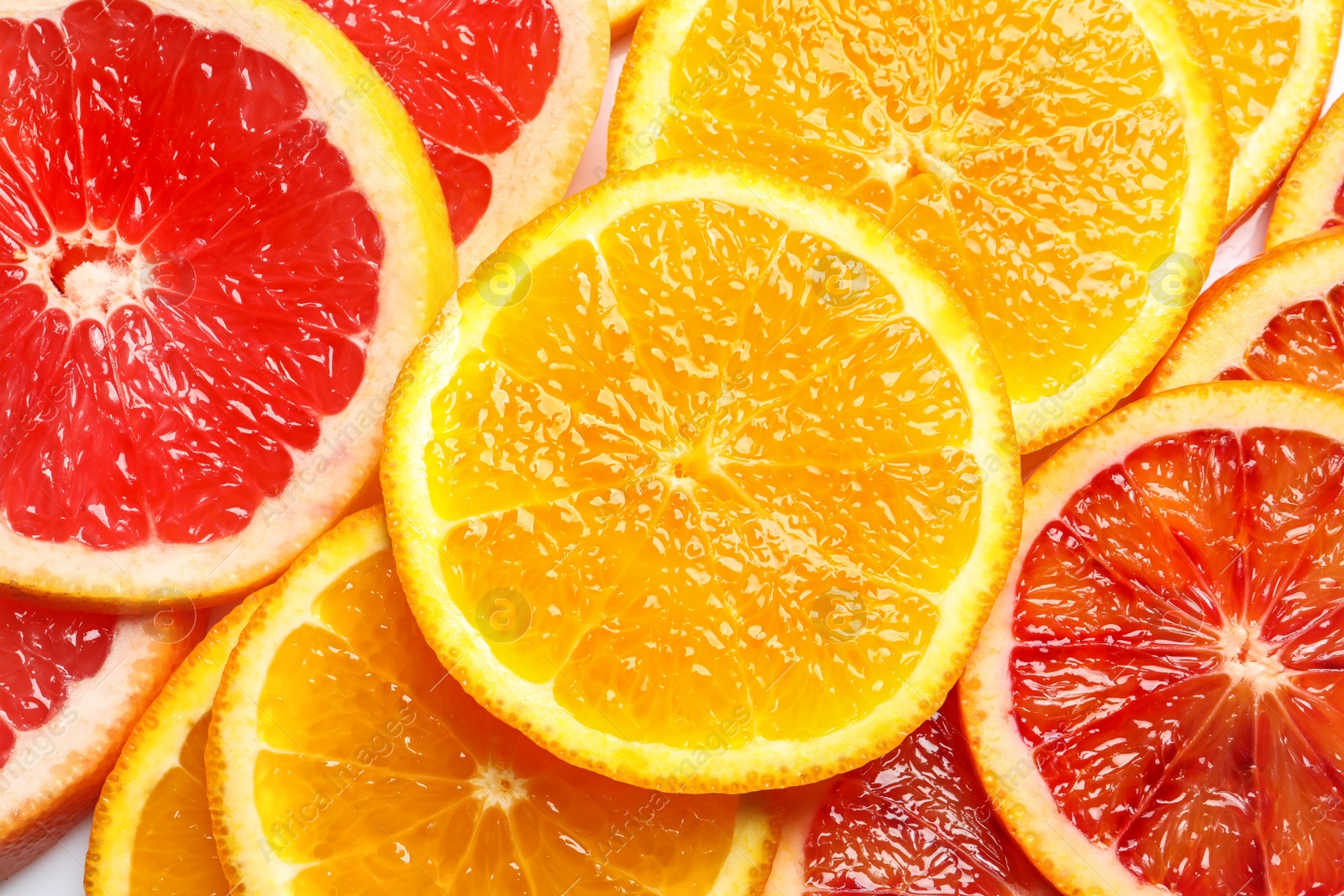 Photo of Slices of fresh citrus fruits as background, top view