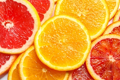 Slices of fresh citrus fruits as background, top view