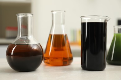 Photo of Flasks and beaker with different types of crude oil on light table