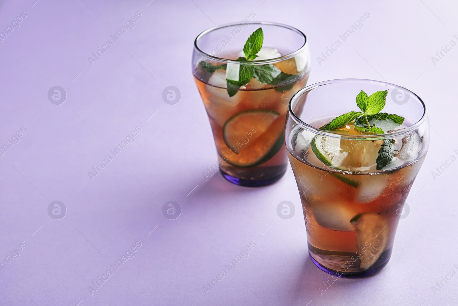 Photo of Glasses of refreshing iced tea on lilac background. Space for text