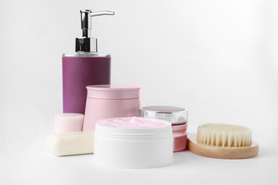 Different body care products and brush on white background