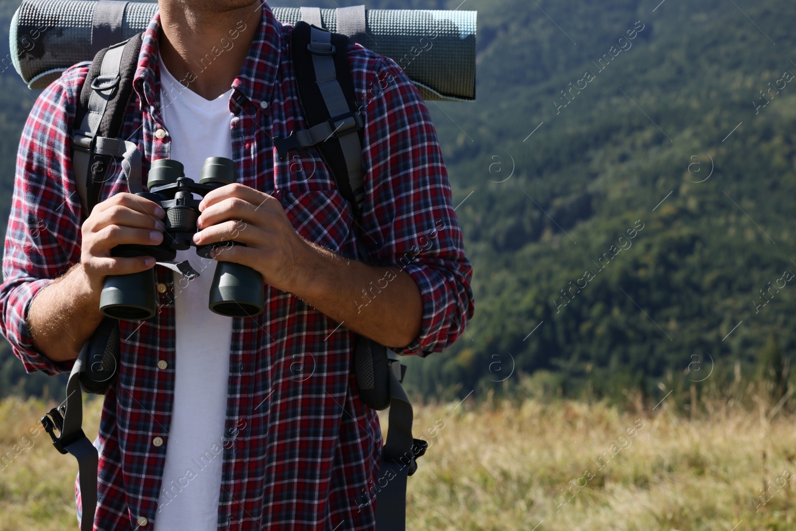 Photo of Tourist with hiking equipment and binoculars in mountains, closeup