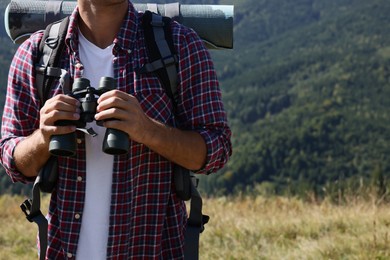 Tourist with hiking equipment and binoculars in mountains, closeup