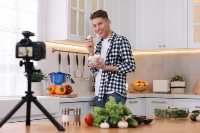 Photo of Smiling food blogger with mushrooms recording video in kitchen