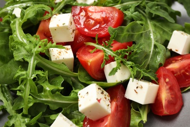 Photo of Delicious salad with feta cheese, arugula and tomatoes on plate, closeup