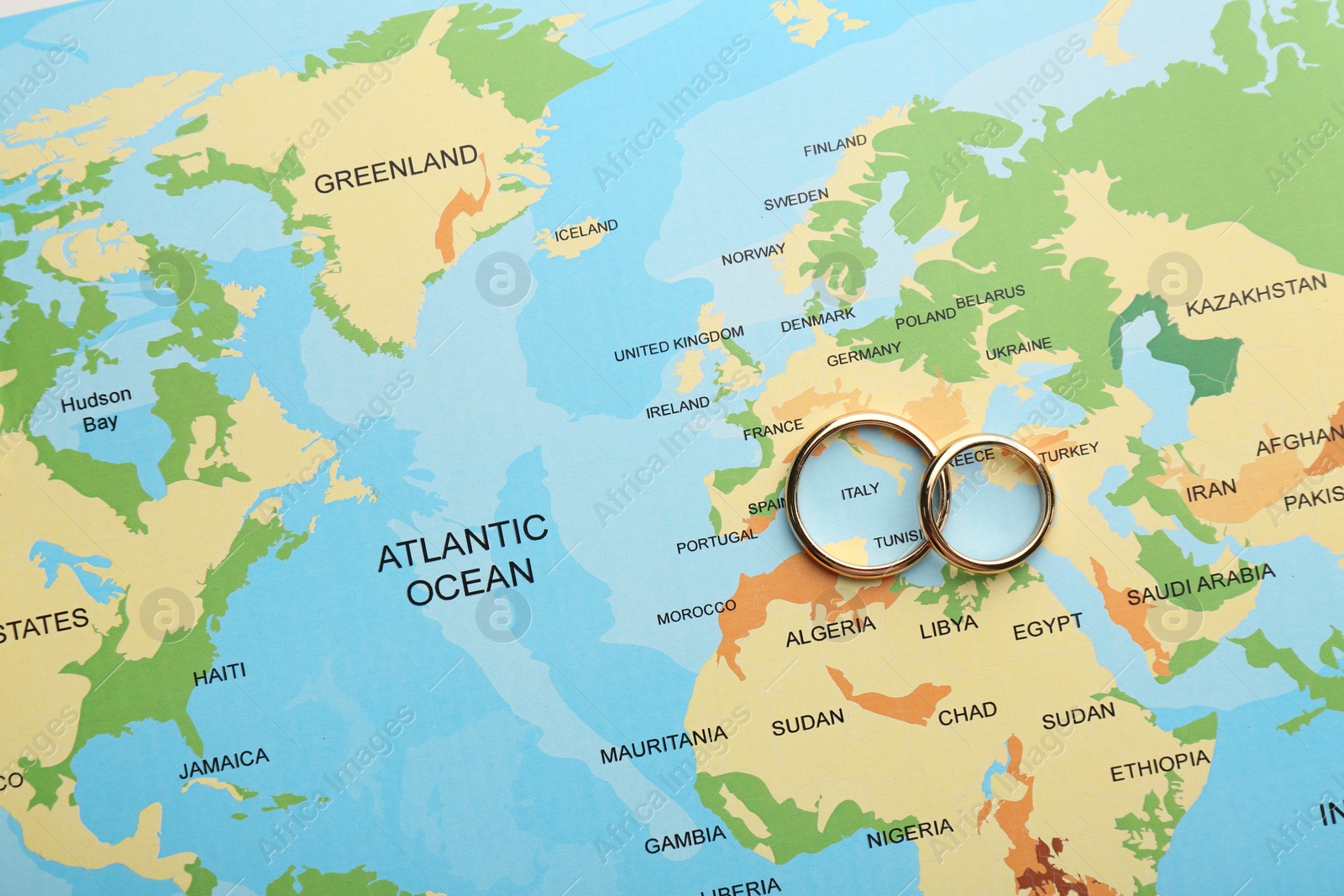 Photo of Honeymoon concept. Two golden rings on world map, top view