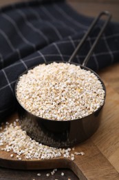 Photo of Raw barley groats in scoop on table, closeup