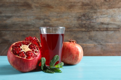 Glass of pomegranate juice and fresh fruits on table against wooden background, space for text