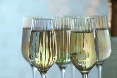 Glasses and bottle of champagne against blurred lights, closeup