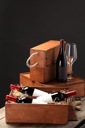 Photo of Boxes with wine bottles and glass on wooden table against black background