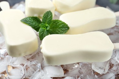 Glazed ice cream bars served with fresh mint on ice cubes, closeup