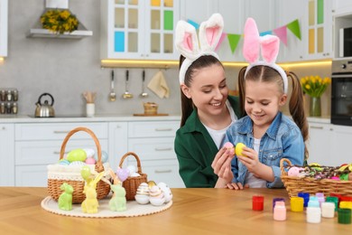 Photo of Mother and her daughter with Easter eggs at table in kitchen