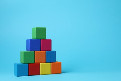 Photo of Pyramid of blank colorful cubes on light blue background. Space for text