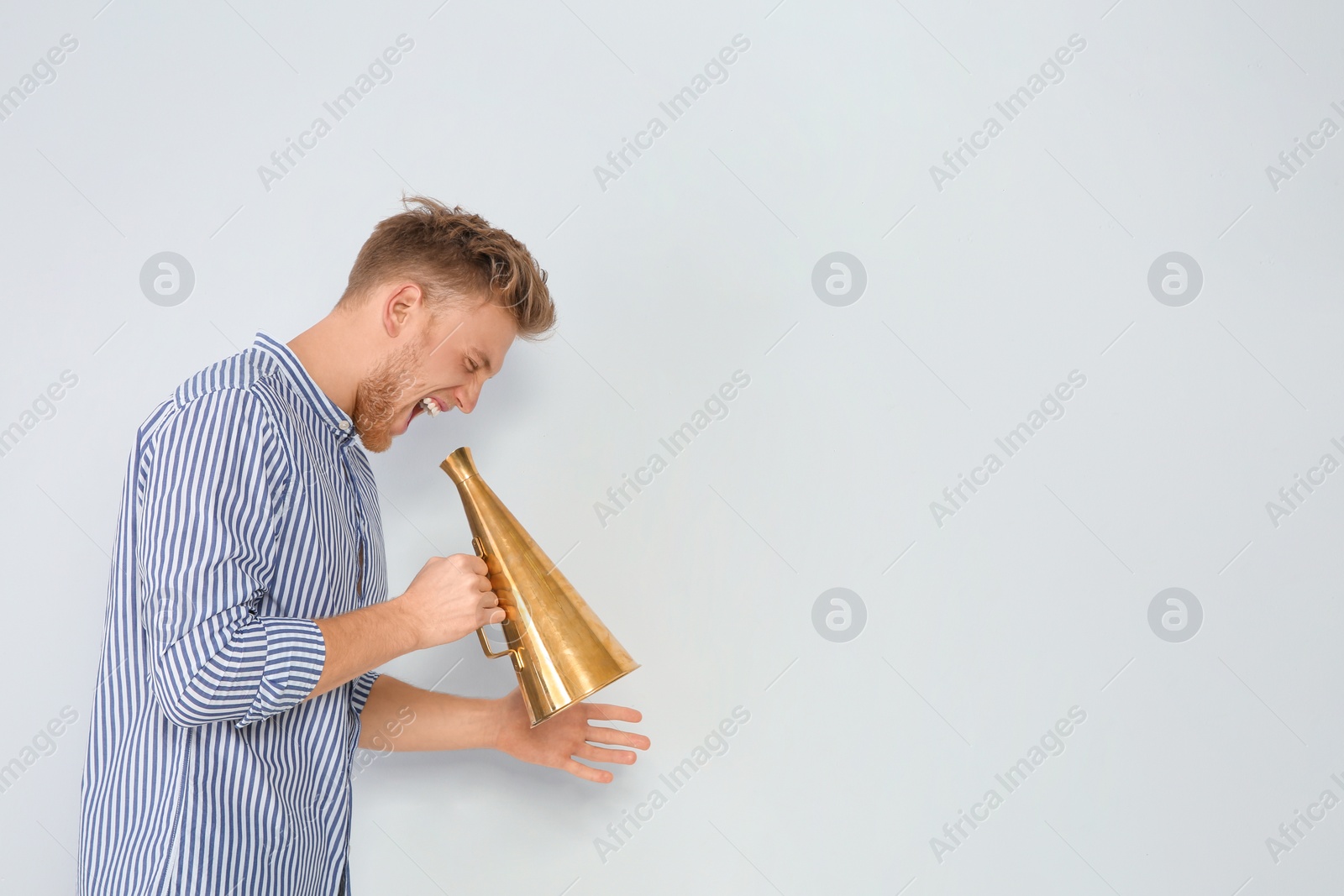 Photo of Young man with megaphone on light background. Space for text
