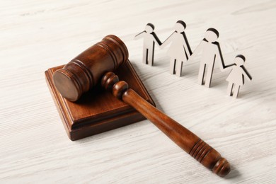 Photo of Law concept. Gavel and figures of parents with children on white wooden table