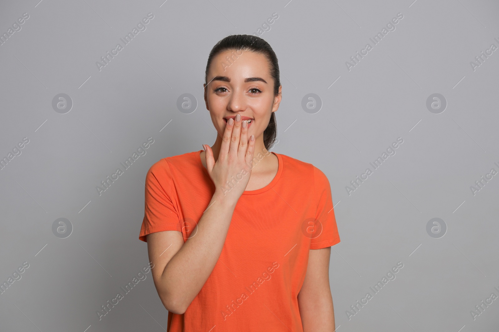 Photo of Beautiful young woman laughing on grey background. Funny joke