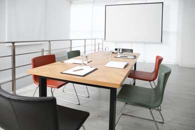 Photo of Modern meeting room interior with large table and projection screen