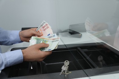 Cashier with money at currency department window in bank, closeup