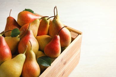 Photo of Wooden crate with ripe pears on light background. Space for text