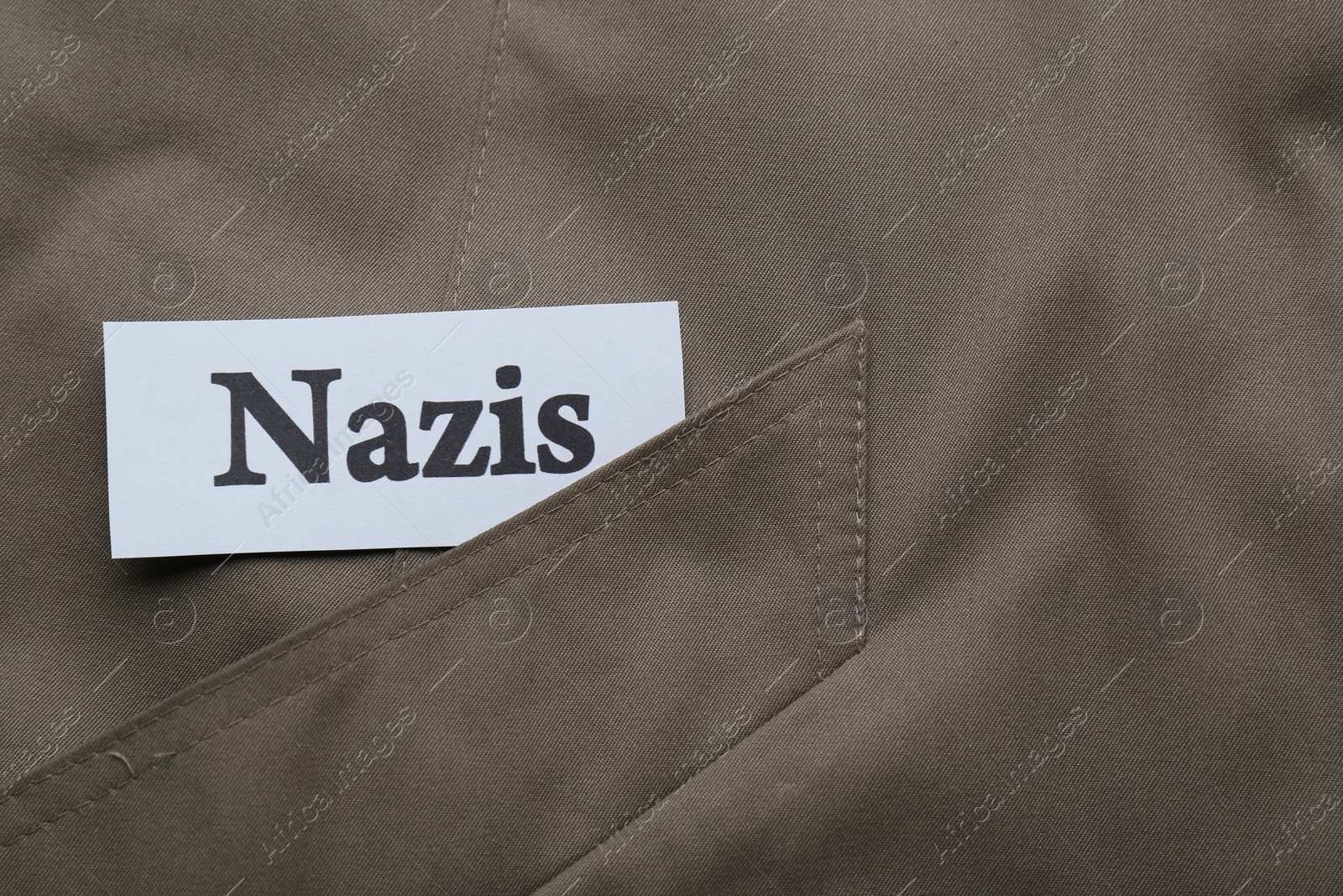 Photo of Card with word Nazis on grey jacket, top view