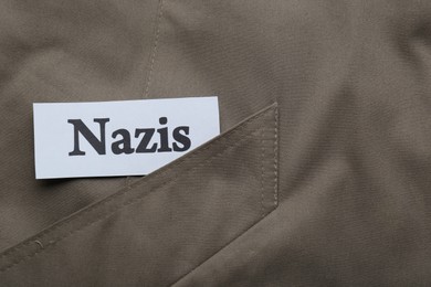 Photo of Card with word Nazis on grey jacket, top view